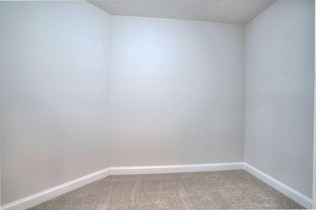 carpeted spare room featuring a textured ceiling and baseboards