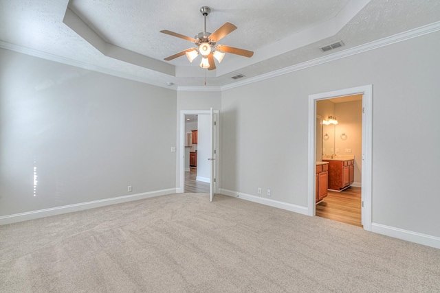 unfurnished bedroom with a raised ceiling, ornamental molding, light carpet, a textured ceiling, and baseboards