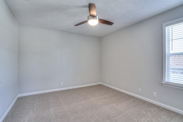 carpeted empty room featuring a ceiling fan, a wealth of natural light, and baseboards