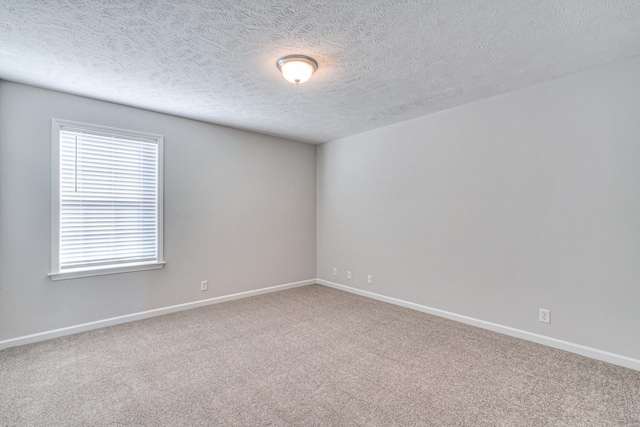 carpeted spare room featuring a textured ceiling and baseboards