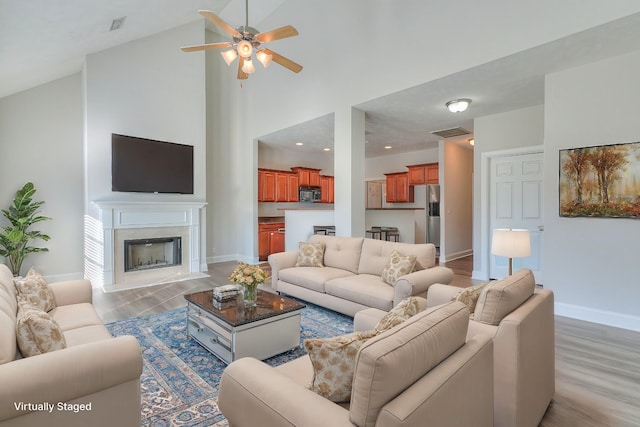 living room featuring a premium fireplace, wood finished floors, visible vents, and baseboards