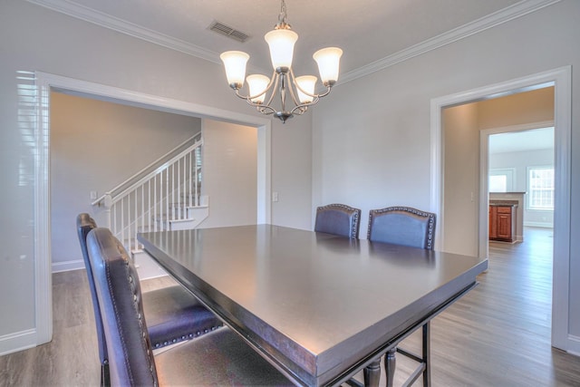 dining area with crown molding, visible vents, a chandelier, and wood finished floors