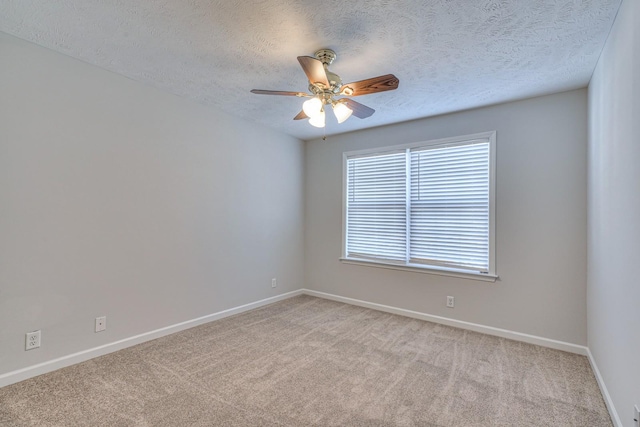 empty room featuring a ceiling fan, light colored carpet, a textured ceiling, and baseboards