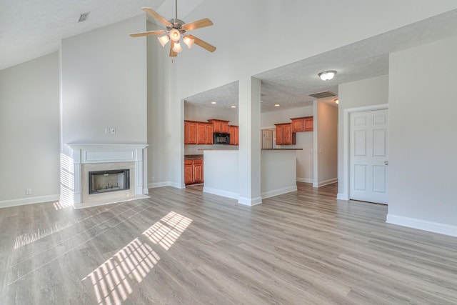 unfurnished living room featuring light wood-type flooring, visible vents, a fireplace, and baseboards