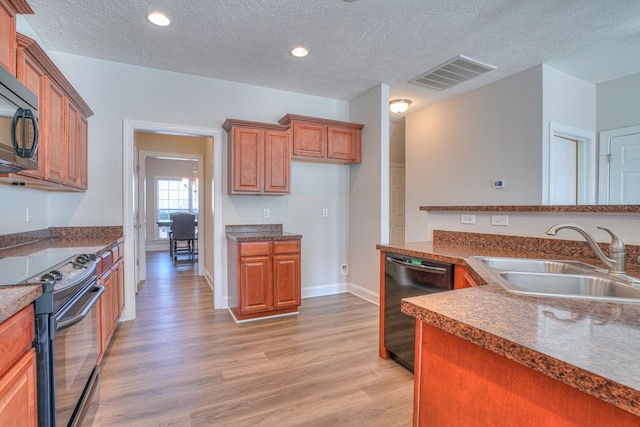 kitchen with a sink, visible vents, light wood-style floors, black appliances, and brown cabinetry