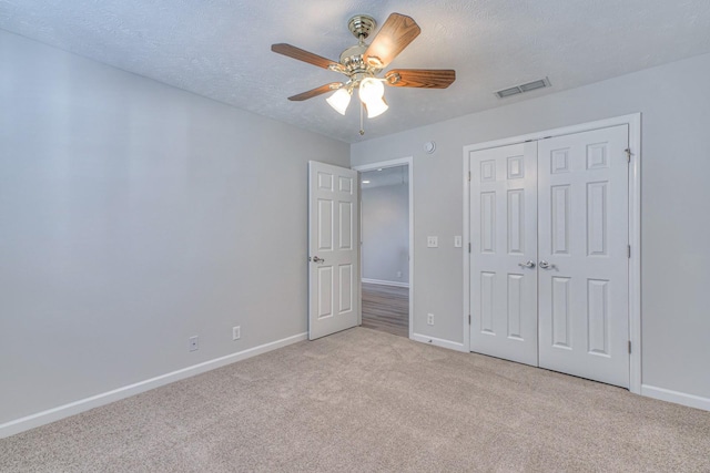 unfurnished bedroom featuring light colored carpet, a textured ceiling, and baseboards