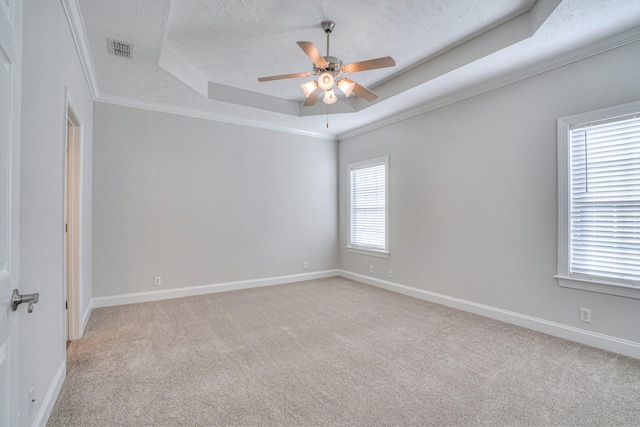 spare room with a tray ceiling, visible vents, light carpet, a textured ceiling, and baseboards