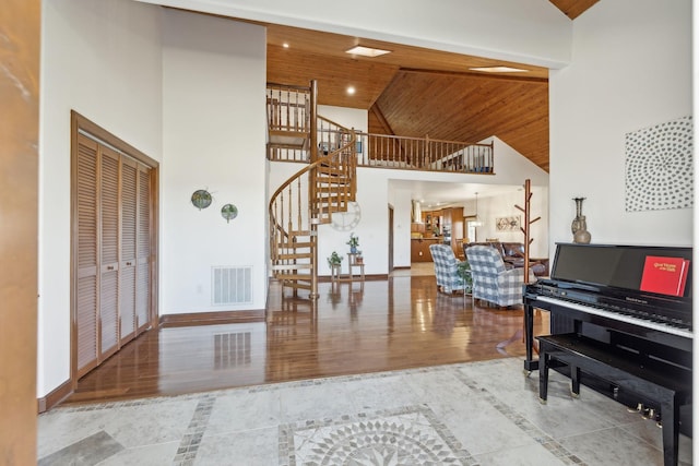 entrance foyer with high vaulted ceiling, wooden ceiling, wood finished floors, visible vents, and baseboards