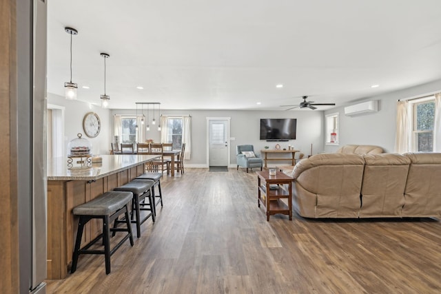 living room featuring recessed lighting, a wall mounted AC, ceiling fan, wood finished floors, and baseboards