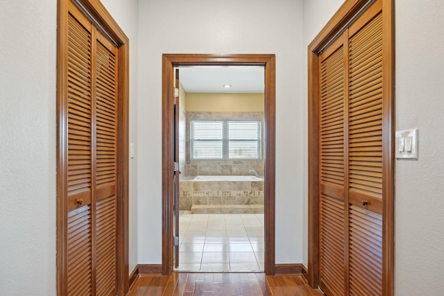 hall with baseboards and wood finished floors