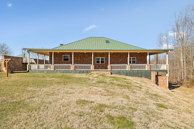 farmhouse-style home with covered porch, a front lawn, metal roof, and a standing seam roof