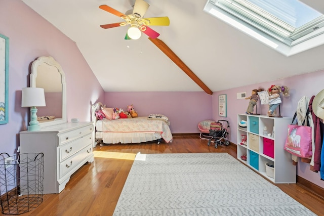 bedroom featuring vaulted ceiling with skylight, wood finished floors, and a ceiling fan