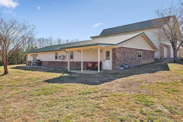 rear view of house featuring a yard, a patio, stucco siding, metal roof, and stone siding