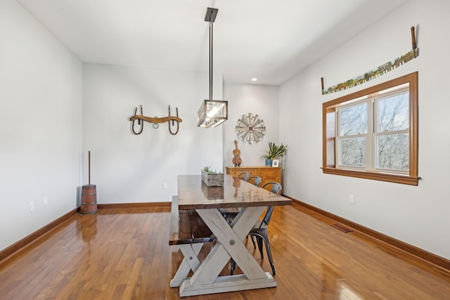 dining room featuring wood-type flooring, visible vents, and baseboards