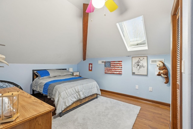 bedroom with lofted ceiling with skylight, wood finished floors, a ceiling fan, and baseboards