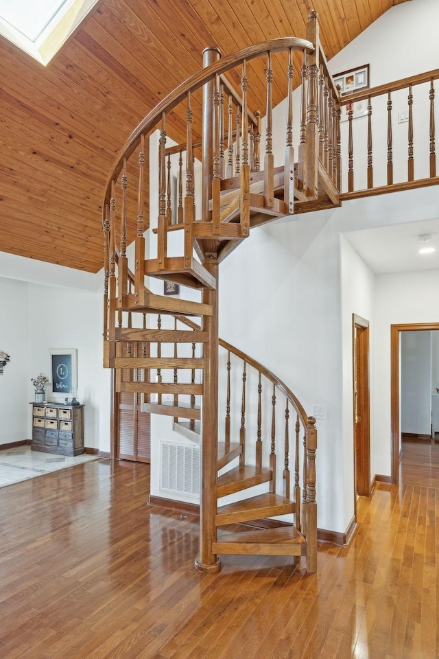 stairway featuring high vaulted ceiling, a skylight, wood ceiling, and wood finished floors