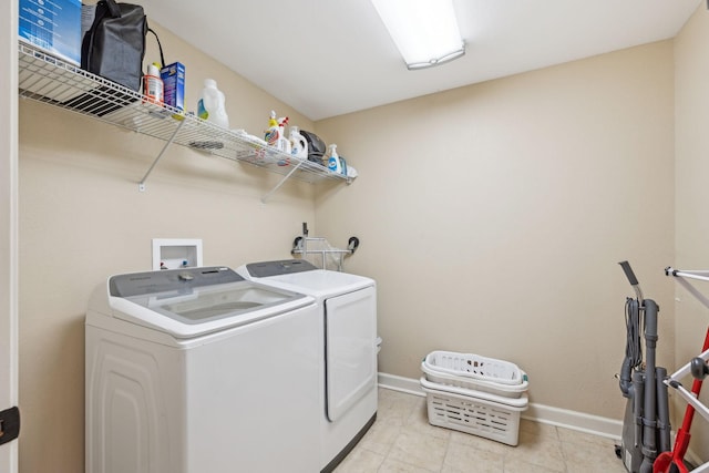 clothes washing area featuring laundry area, light tile patterned floors, baseboards, and separate washer and dryer