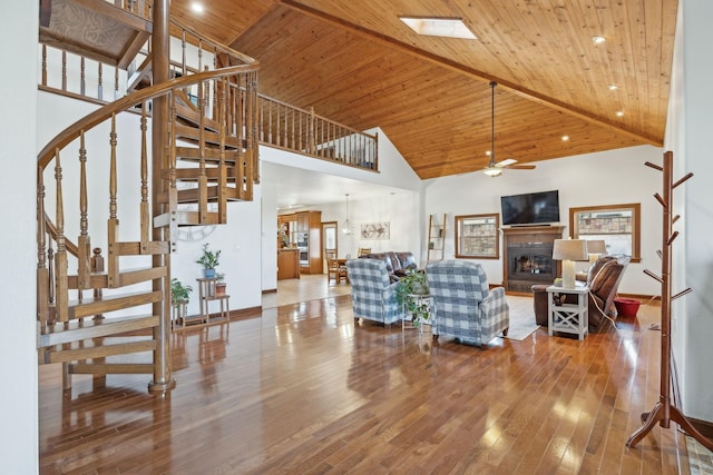 living area featuring stairs, a fireplace, wood finished floors, and wooden ceiling