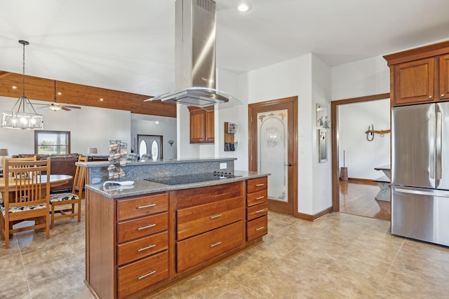 kitchen featuring black electric cooktop, island range hood, freestanding refrigerator, brown cabinetry, and dark stone countertops