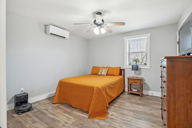 bedroom with light wood finished floors, a wall mounted air conditioner, and baseboards