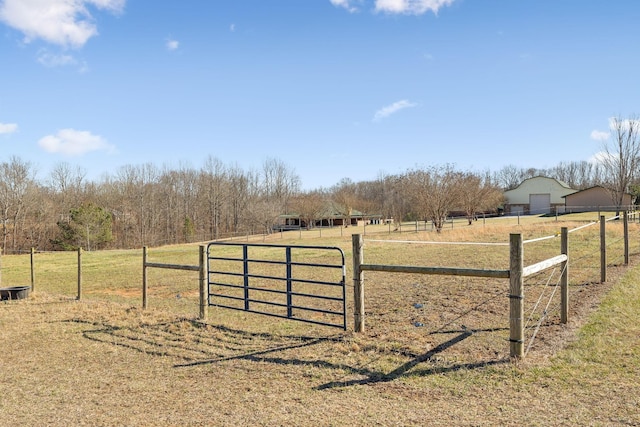 view of gate with a yard, a rural view, and fence