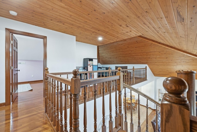 hallway featuring baseboards, lofted ceiling, wood ceiling, wood finished floors, and an upstairs landing