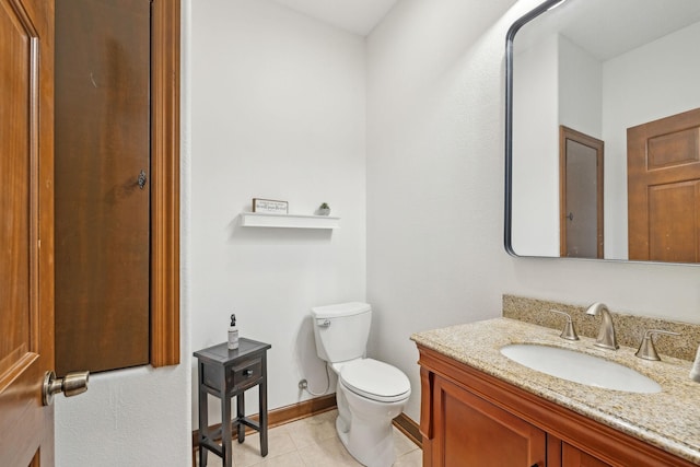 bathroom with toilet, tile patterned floors, baseboards, and vanity