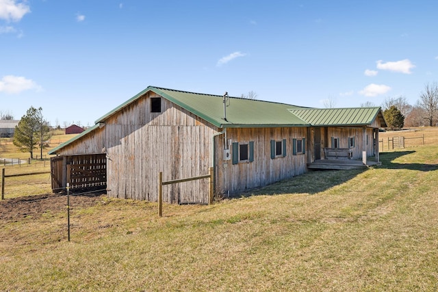 rear view of house with metal roof, a yard, an outbuilding, and fence