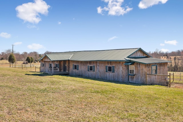 back of property with metal roof, a lawn, and fence