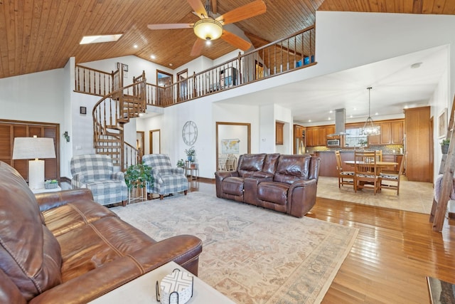 living area featuring light wood finished floors, wood ceiling, stairway, high vaulted ceiling, and ceiling fan with notable chandelier