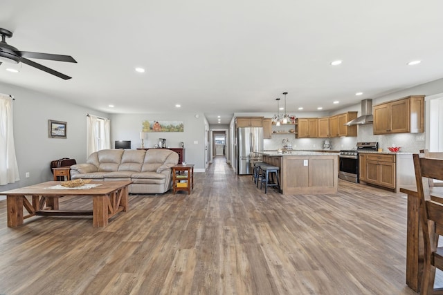 living area with light wood finished floors, baseboards, a ceiling fan, and recessed lighting