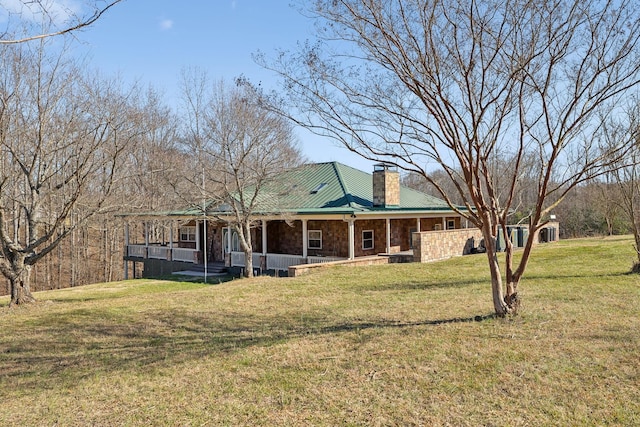 view of front of house featuring stone siding, a chimney, a porch, and a front yard