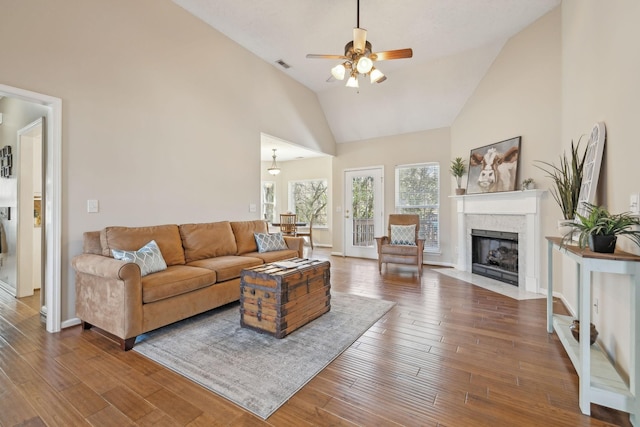 living area featuring a fireplace with flush hearth, high vaulted ceiling, wood finished floors, and visible vents