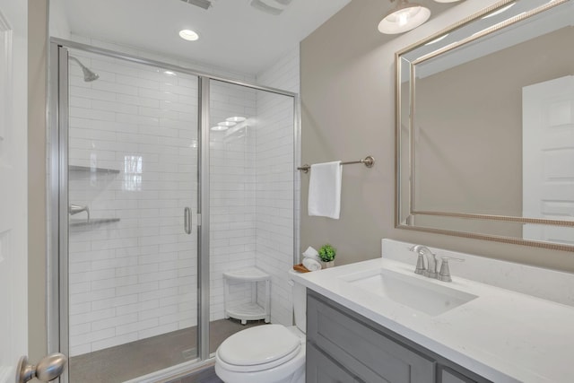 bathroom featuring vanity, a shower stall, and toilet