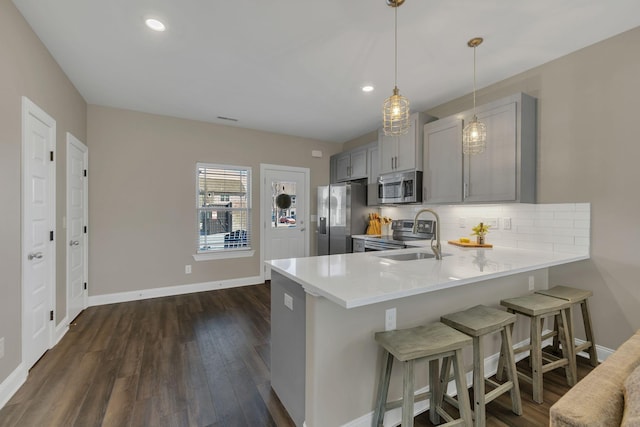 kitchen with decorative backsplash, a breakfast bar area, stainless steel appliances, light countertops, and a sink