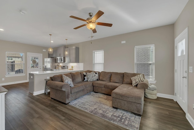 living room featuring ceiling fan, dark wood-style flooring, and baseboards