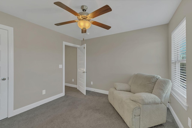 sitting room featuring carpet, baseboards, and a ceiling fan