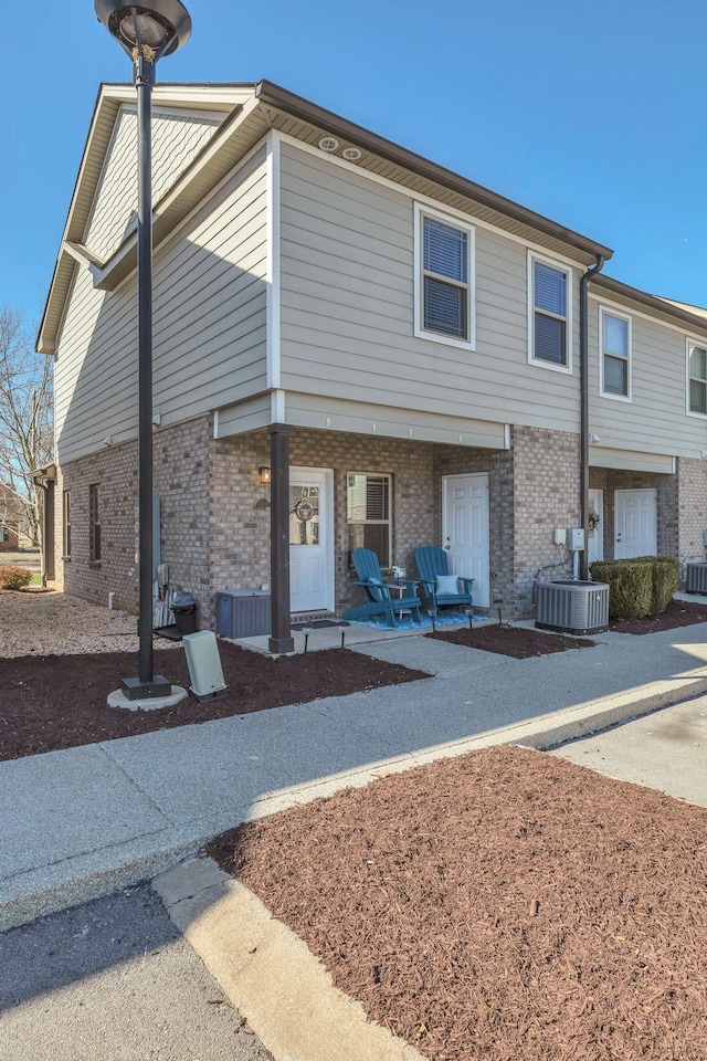 townhome / multi-family property featuring central air condition unit, a patio area, and brick siding