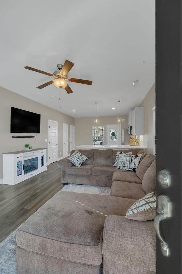 living area with dark wood finished floors, baseboards, and ceiling fan