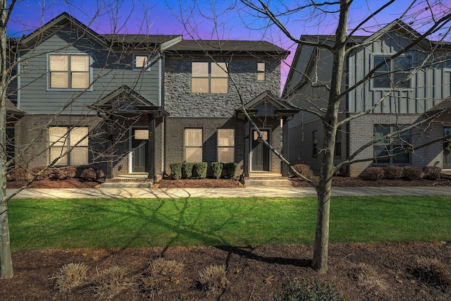 view of front facade with a yard and brick siding