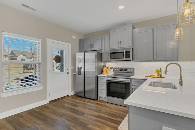 kitchen featuring visible vents, decorative backsplash, gray cabinets, stainless steel appliances, and a sink