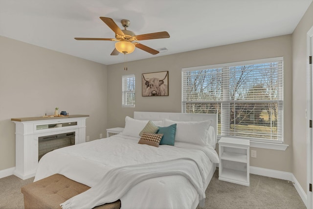 carpeted bedroom featuring multiple windows, baseboards, a fireplace, and a ceiling fan