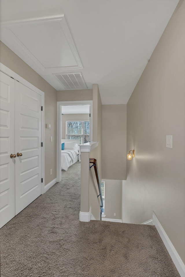 hallway with baseboards, visible vents, carpet flooring, and an upstairs landing