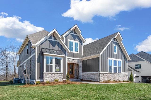 craftsman house featuring stone siding, central AC unit, board and batten siding, and a front lawn