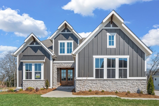 view of front of house featuring a front lawn, french doors, board and batten siding, and stone siding