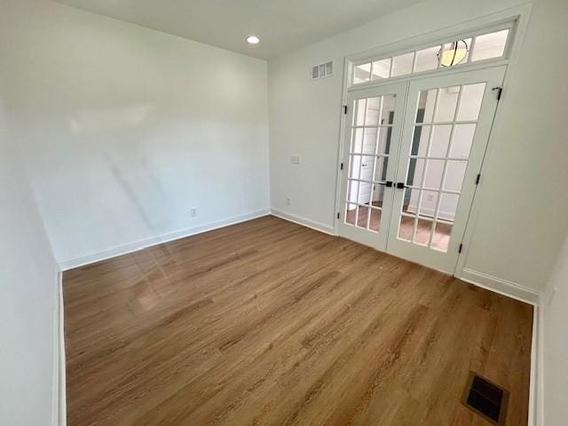 empty room with french doors, visible vents, baseboards, and wood finished floors