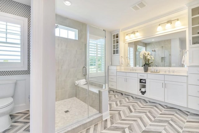 bathroom with toilet, a sink, visible vents, double vanity, and a stall shower