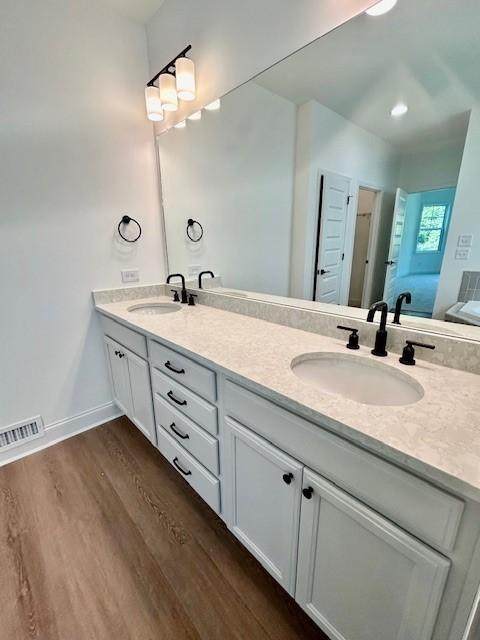 bathroom featuring double vanity, wood finished floors, a sink, and baseboards