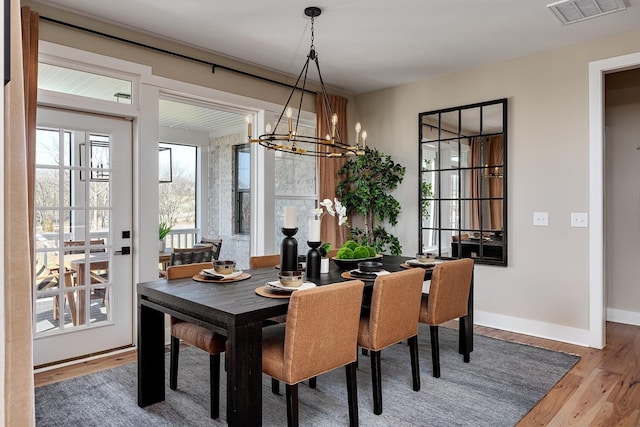 dining space with a chandelier, wood finished floors, visible vents, and baseboards