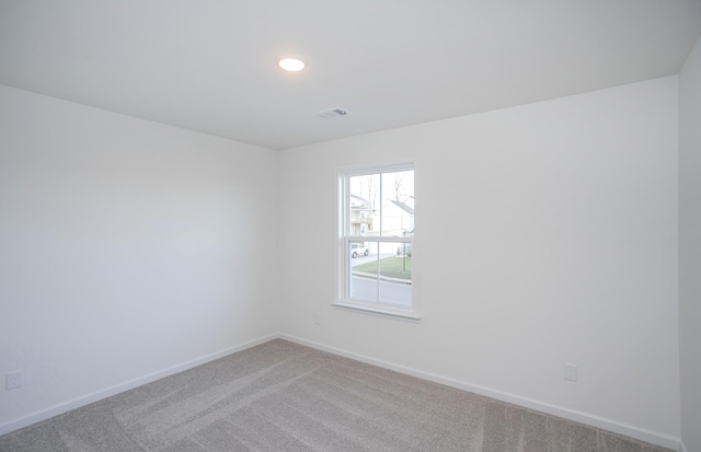 unfurnished room with carpet flooring, visible vents, and baseboards